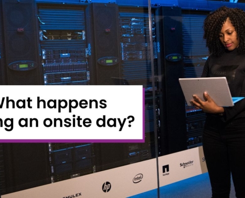 Woman with laptop standing next to a server rack