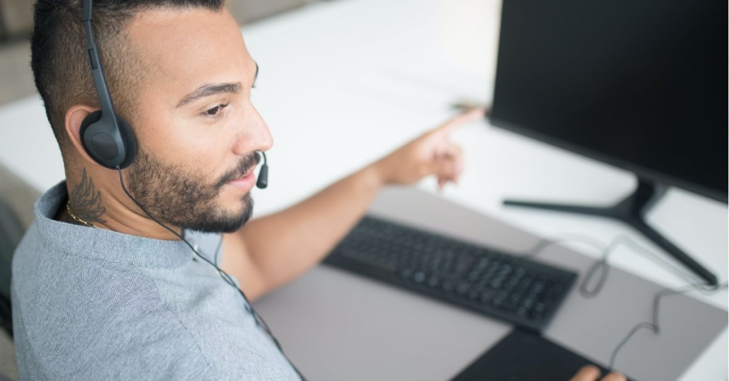 Man working at laptop with headset on to represent Small business network support services - Proactive network monitoring