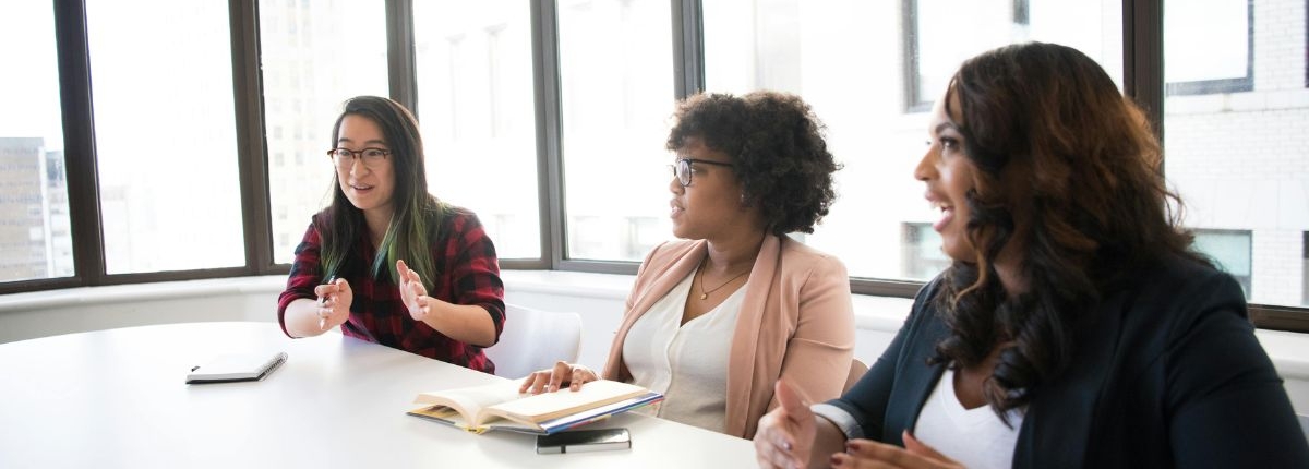 Three women at a conference room table illustrating IT business consulting