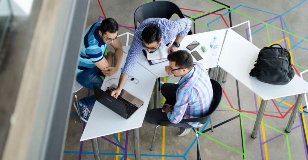 Group of office workers gathered around a laptop to illustrate network support services
