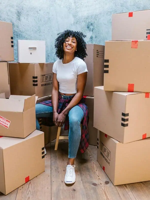 Young woman sitting in a pile of moving boxes illustrating office IT relocation services
