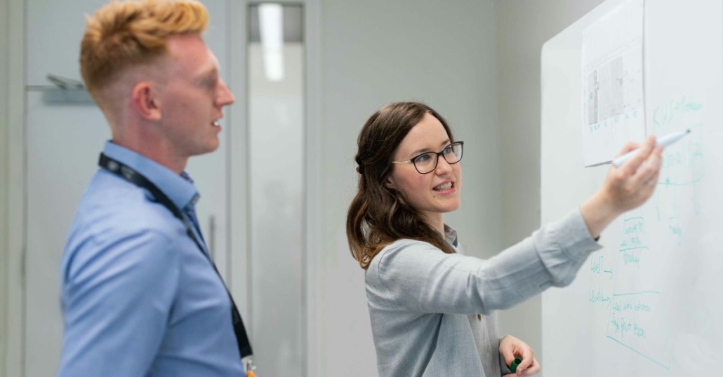 Business person and technician consulting a whiteboard